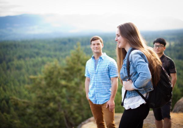 Three students stand on a hill overlooking the Cowichan valley